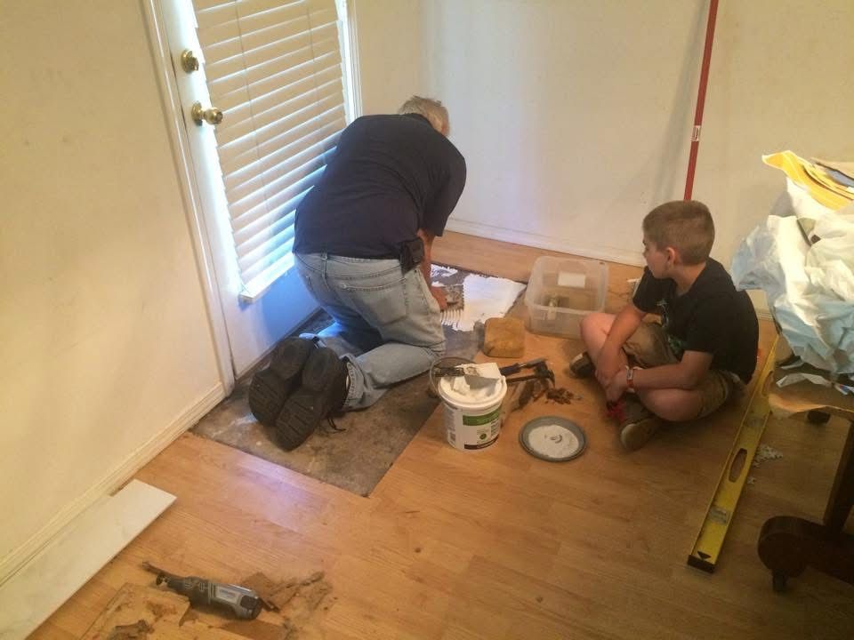 Patriot crew setting a tile inlay, with a young helper watching